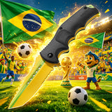 A Brazil world cup football  folding knife with a black textured handle and a gold blade with green accents is shown in a dramatic soccer stadium scene with Brazil flags, footballs, a trophy, and a cheering cartoon player.