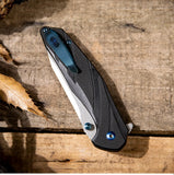 Folding knife on a wooden surface with leaves