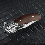 A folded pocket knife with a Damascus pattern blade and a dark rosewood handle, displayed on a dark textured surface.